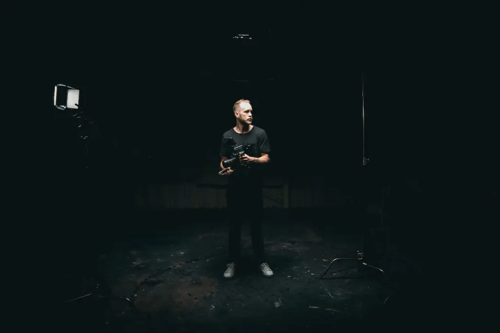 A photo of a camera man standing in the dark room