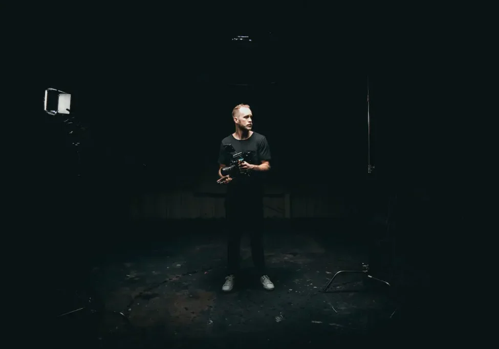 A photo of a camera man standing in the dark room